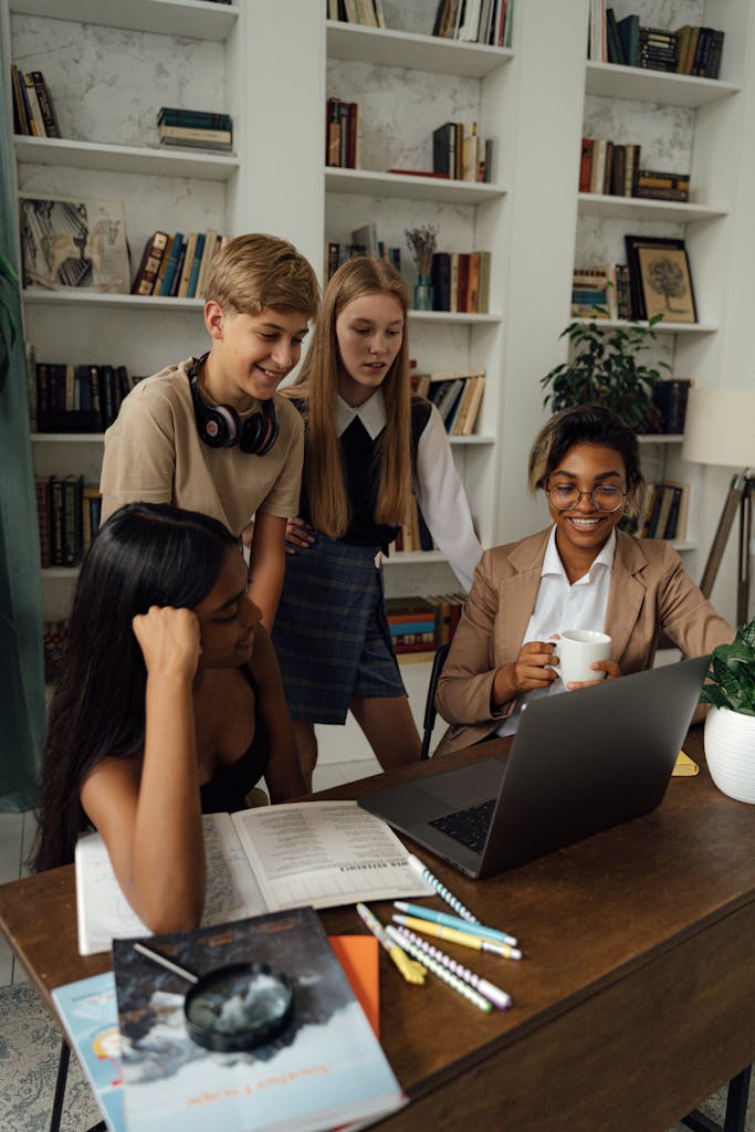 Group of teenagers studying and collaborating with a teacher in a library setting.