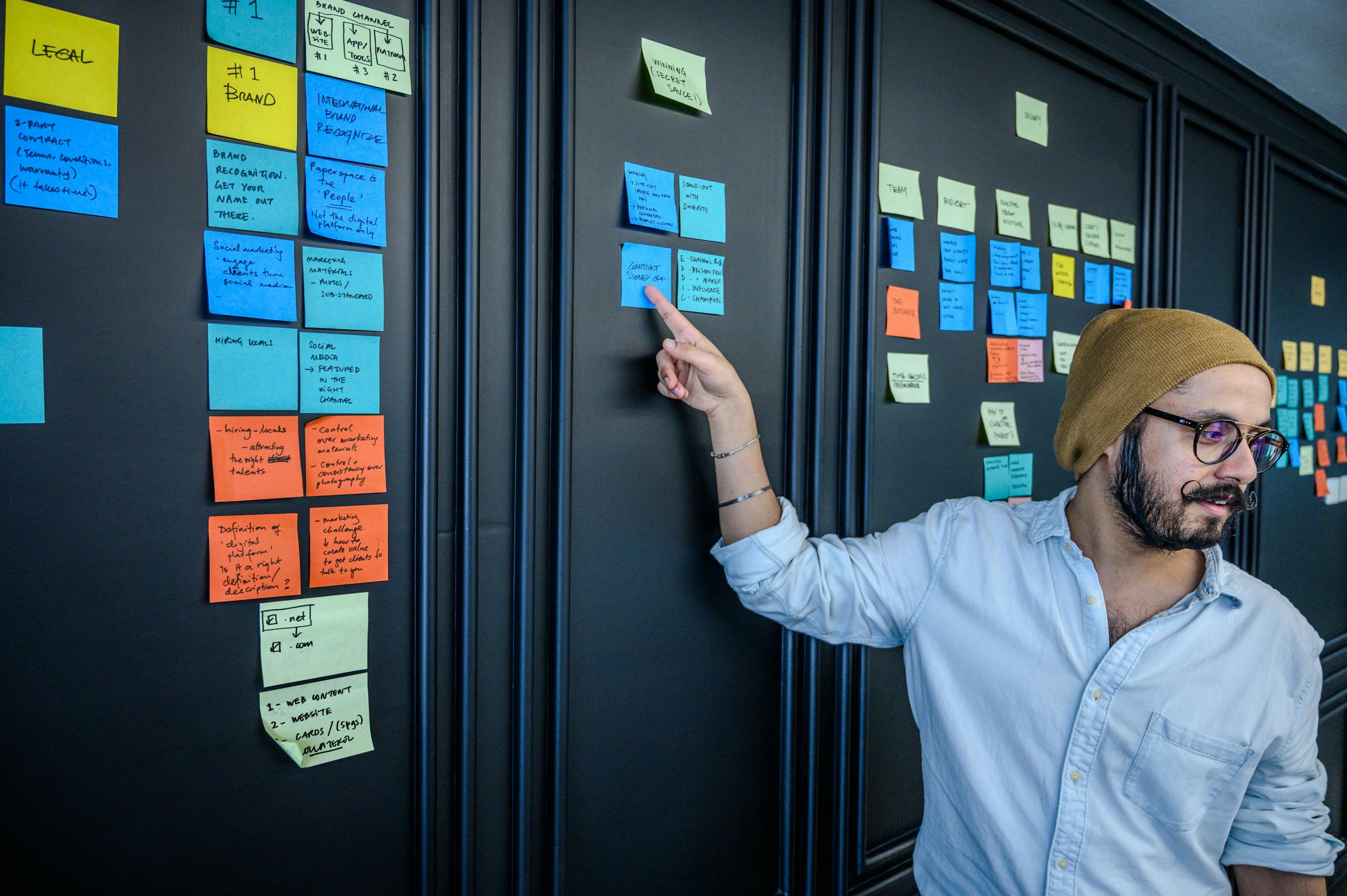 Bearded entrepreneur points at sticky notes during a business strategy session.