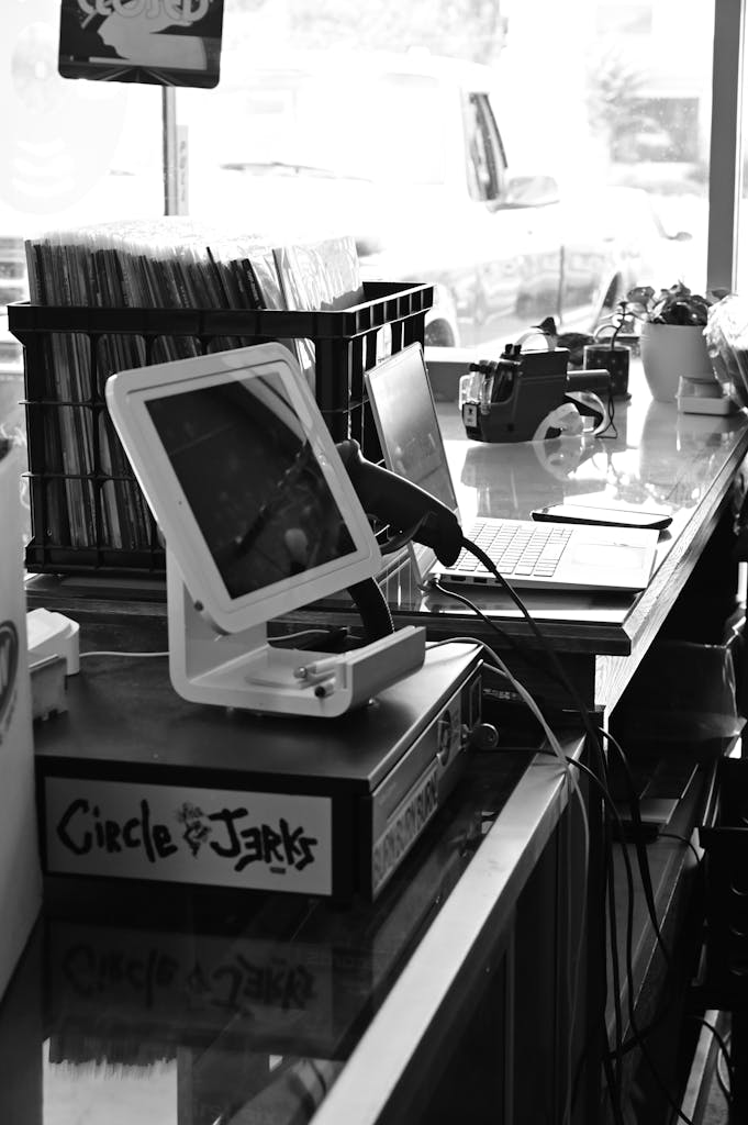 Black and white photo of vinyl records and modern tech in a vintage store.