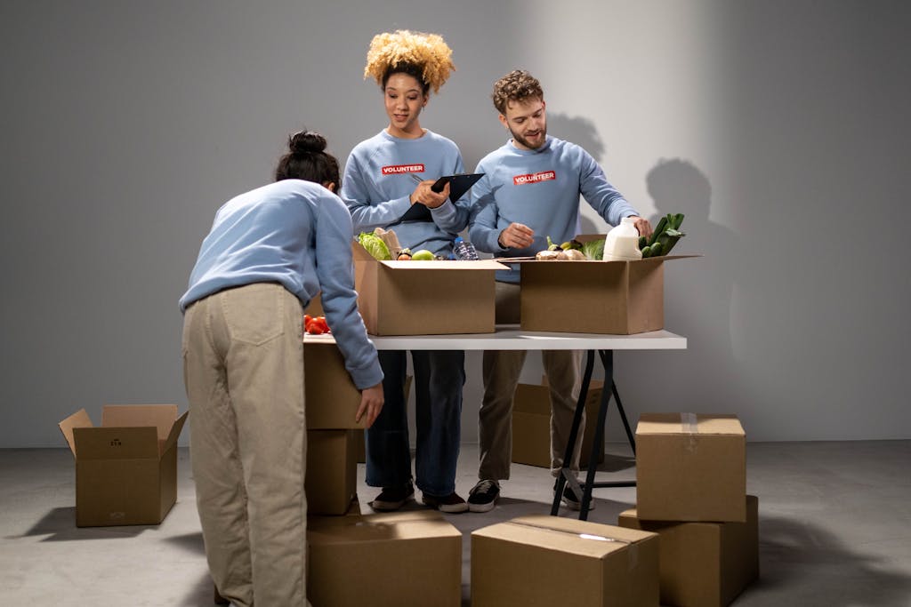 Three volunteers organizing food donations into boxes, showing teamwork and community support.